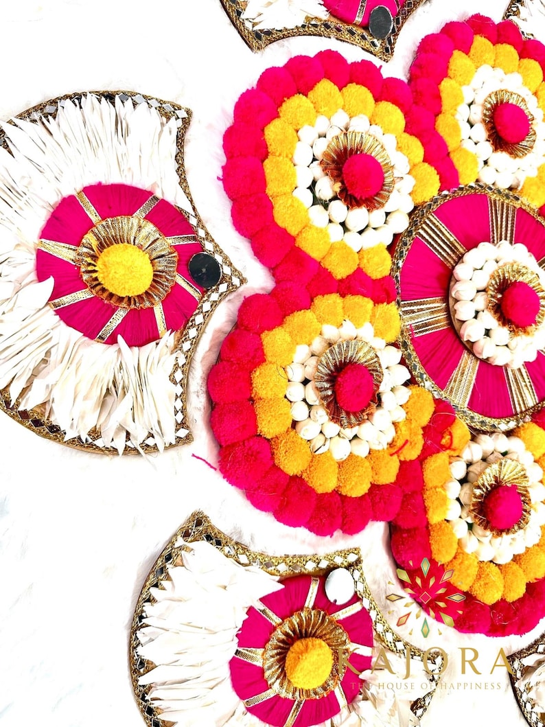 May include: A set of decorative round floral arrangements with pink, yellow, and white pom-poms. The arrangements are on a white background.