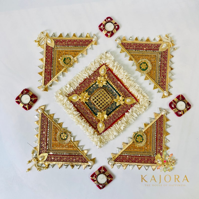 May include: A set of five gold and red decorative wall hangings with intricate designs and embellishments. The hangings are arranged in a square pattern with a white square in the center. The white square has a gold and green design with a fringe border. The hangings are surrounded by four small red square candle holders.