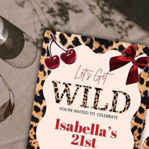 May include: Two party invitations with a leopard print border and the words "Let's Get WILD" in a bold font. The invitations also include the text "You're invited to celebrate Isabella's 21st" in red. The design includes red cherries and bows.
