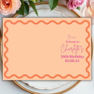 以下が含まれることがあります： 波打つオレンジ色の縁取りのあるピーチ色の席札。テキストは「Welcome to Charlotte's 30th Birthday 10.08.24」です。