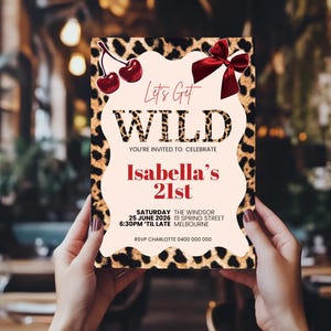 May include: A party invitation with a leopard print border and the words "Let's Get WILD" in a bold font. The invitation includes the text "Isabella's 21st" and event details. Decorative cherries and a red bow adorn the top.