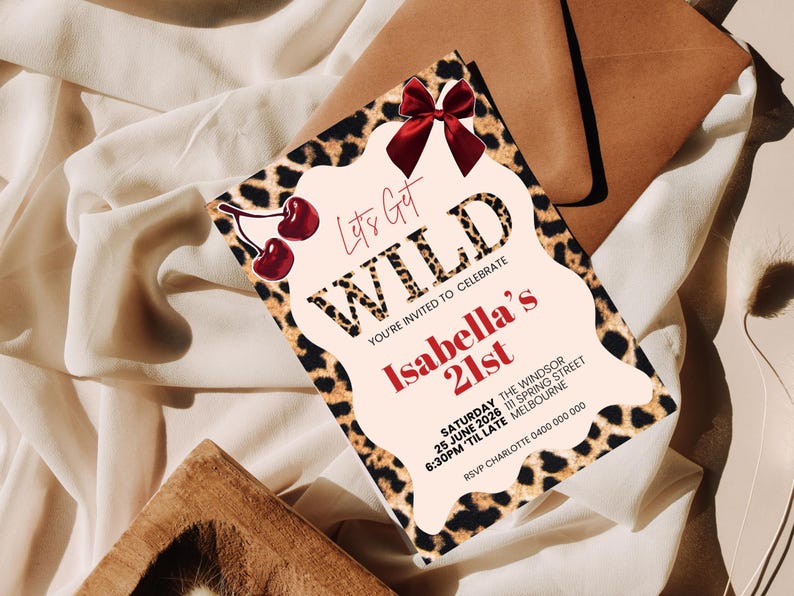 May include: A party invitation with a leopard print border and the words "Let's Get WILD" in bold letters. The invitation is for Isabella's 21st birthday, with details including the date, time, and location. A red bow and cherries add a decorative touch.