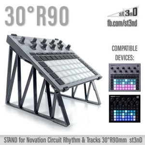 May include: Black metal stand for a Novation Circuit Rhythm or Tracks music production controller. The stand is angled at 30 degrees and is 90mm wide. The stand is compatible with the Novation Circuit Rhythm and Tracks devices. The stand is made by st3nD. The stand is shown with a Novation Circuit Rhythm and Tracks device on top of it.