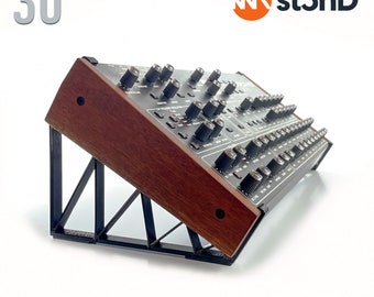 May include: A black metal stand with a wooden top, angled at 30 degrees, designed to support a Sequential Prophet Rev2 synthesizer. The stand is labelled "st3nD" and "STAND for SEQUENTIAL PROPHET REV2 - 30° - st3nD".