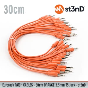 May include: A bundle of orange 3.5mm TS jack patch cables, each 30cm (11.8 inches) long. The cables are neatly arranged and tied together. The text "st3nD" and "Eurorack Patch Cables" are visible.