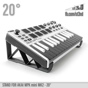 May include: A white and black AKAI MPK mini keyboard on a black stand, angled at 20 degrees. The keyboard has black keys and control pads, with the text "AKAI MPK mini" visible. The stand is labelled "STAND FOR AKAI MPK mini MK2 - 20°".