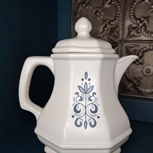 May include: White ceramic teapot with a blue and white floral design. The teapot has a lid and a handle.