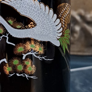 May include: Black bottle with a white crane and gold and green floral design.