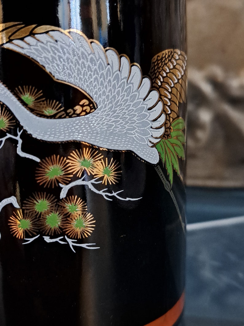 May include: Black bottle with a white crane and gold and green floral design.