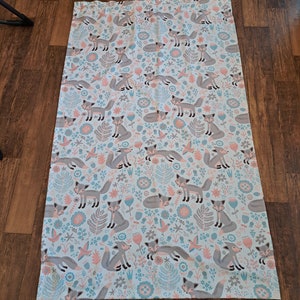May include: A white fabric curtain with a repeating pattern of gray foxes, pink flowers, and blue leaves.