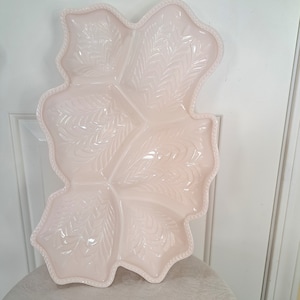 May include: A pink glass serving dish shaped like a leaf with five sections. The dish has a raised, embossed design of leaves and is trimmed with a beaded edge.