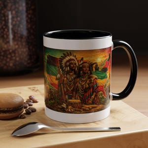 May include: White ceramic mug with a black interior and handle. The mug features a colorful illustration of two figures in traditional attire, set against a backdrop of a flag and a map. The mug is on a wooden surface.