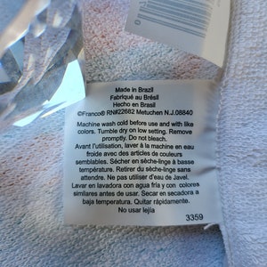 May include: White care label with black text detailing washing instructions for a garment. The label reads "Made in Brazil, Fabriqu&eacute; au Br&eacute;sil, Hecho en Brasil, &copy;Franco&reg; RN#22682 Metuchen N.J.08840, Machine wash cold before use and with like colors. Tumble dry on low setting. Remove promptly. Do not bleach. Avant l'utilisation, laver &agrave; la machine en eau froide avec des articles de couleurs semblables. S&eacute;cher en s&egrave;che-linge &agrave; basse temp&eacute;rature. Retirer du s&egrave;che-linge sans attendre. Ne pas utiliser d'eau de Javel. Lavar en lavadora con agua fr&iacute;a y con colores similares antes de usar. Secar en secadora a baja temperatura. Quitar r&aacute;pidamente. No usar lej&iacute;a, 3359".