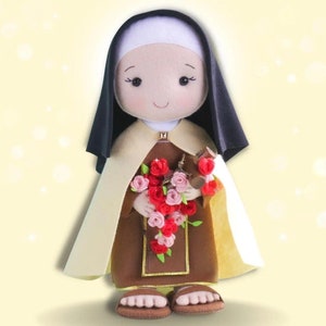 May include: A handmade doll of Saint Th&eacute;r&egrave;se of Lisieux, wearing a brown habit with a white veil and a black scapular. She is holding a bouquet of red and pink roses.