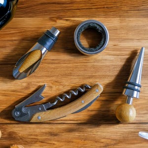 May include: A set of wine accessories including a corkscrew, a bottle stopper, a wine pourer, and a wine ring. The accessories are on a wooden surface.