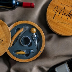 May include: A wooden box with a lid, engraved with the text "Adams Family Est. 2025". The box contains a set of wine tools, including a corkscrew, a bottle stopper, and a foil cutter. The box is open, revealing the tools inside.