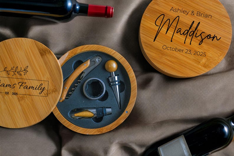 May include: A wooden box with a lid, engraved with the text "Adams Family Est. 2025". The box contains a set of wine tools, including a corkscrew, a bottle stopper, and a foil cutter. The box is open, revealing the tools inside.