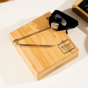 May include: A personalized bamboo serving tray with a set of metal ice cubes and tongs. The tray is engraved with the name "William" and the title "Groomisman".