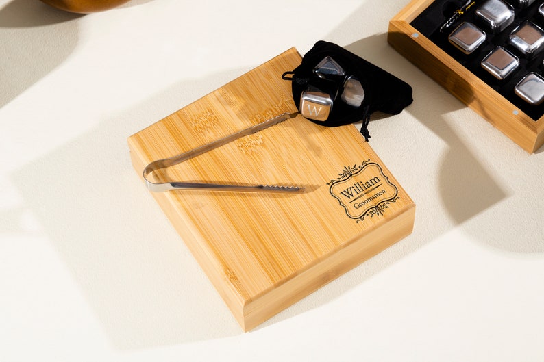 May include: A personalized bamboo serving tray with a set of metal ice cubes and tongs. The tray is engraved with the name "William" and the title "Groomisman".