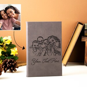 May include: A gray leather-bound journal with a black and white line drawing of a family of four. The journal has the text "Your Text Here" engraved on the front.