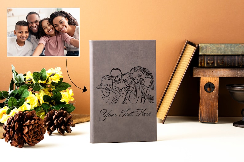 May include: A gray leather-bound journal with a black and white line drawing of a family of four. The journal has the text "Your Text Here" engraved on the front.