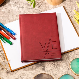 May include: A burgundy leather-bound journal with the initials "V/E" and the names "Vandy Ernie" printed in black on the front cover.