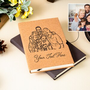 May include: A cork notebook with a black and white line drawing of a family of seven people. The notebook has a black cover and the text "Your Text Here" is printed on the front.