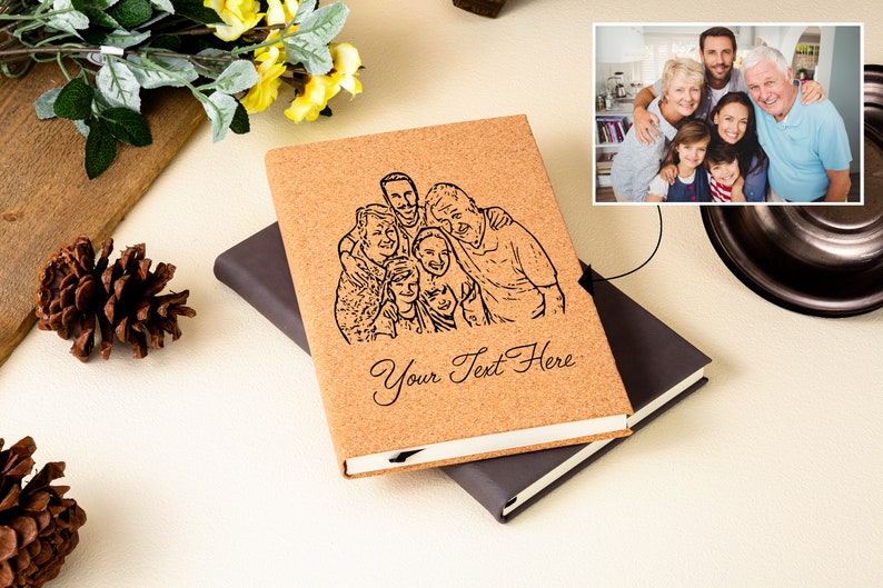 May include: A cork notebook with a black and white line drawing of a family of seven people. The notebook has a black cover and the text "Your Text Here" is printed on the front.