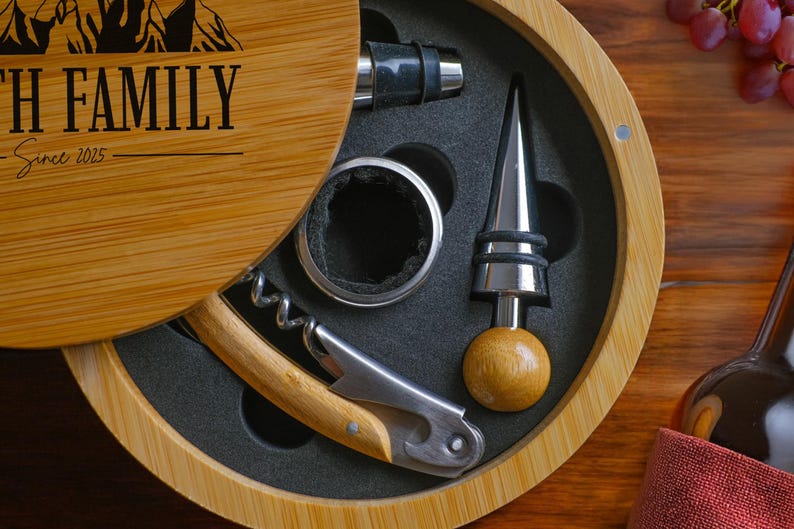 May include: A wooden box with a lid that opens to reveal a wine opener set. The set includes a corkscrew, a bottle stopper, a pourer, and a foil cutter. The box is engraved with the text "With Family Since 2025".