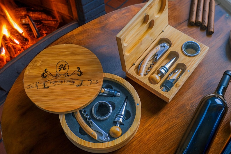 May include: A wooden box with a personalised inscription, "H.  Hinsley Family", containing a wine opener, bottle stopper, and other wine accessories. The box is open and the accessories are visible.