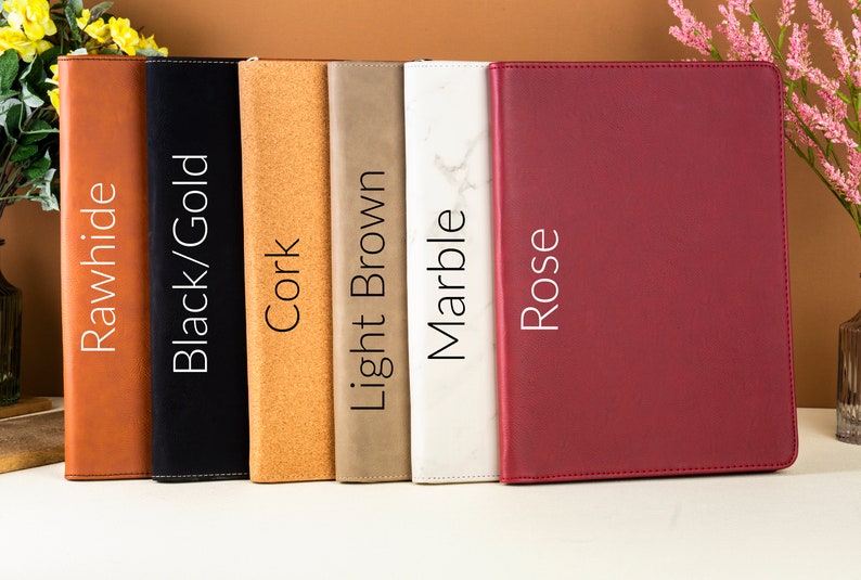May include: A collection of six leather-bound journals in various colors: Rawhide, Black/Gold, Cork, Light Brown, Marble, and Rose. Each journal has a different texture and color, with the names of the colors printed vertically on the spine.