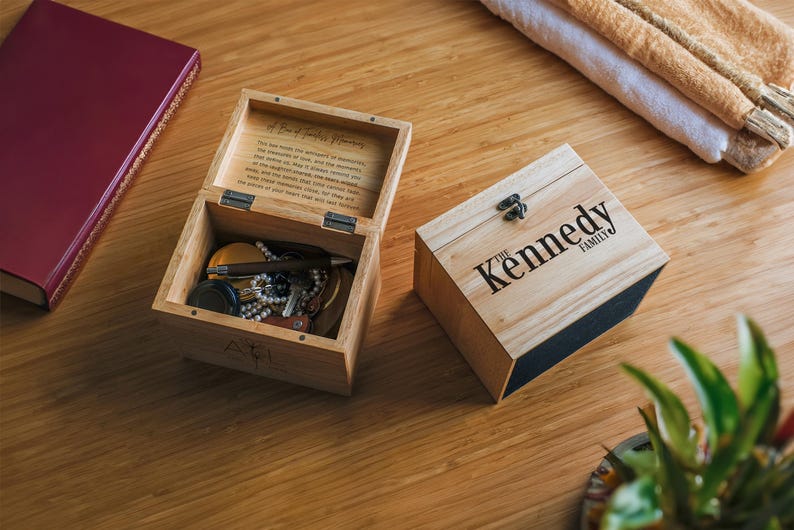 May include: Two wooden boxes, one open and one closed. The open box contains various trinkets and is labeled "A Box of Happy Memories". The closed box is labeled "The Kennedy Family".