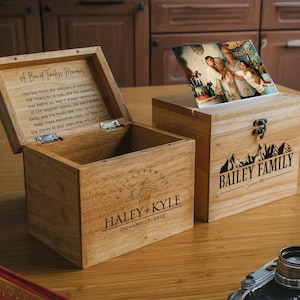 May include: Two wooden boxes with lids open. The box on the left has the text "A Box of Timeless Memories" and "Haley + Kyle December 22, 2015" engraved on the front. The box on the right has the text "Bailey Family Since 2007" engraved on the front. Both boxes are made of light brown wood.