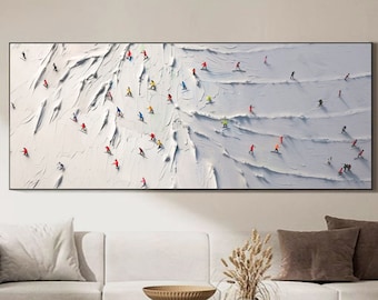 May include: A white canvas painting depicting a snowy mountain scene with skiers and snowboarders in various colors. The skiers and snowboarders are small and appear to be moving down the mountain. The painting has a textured, brushstroke effect.