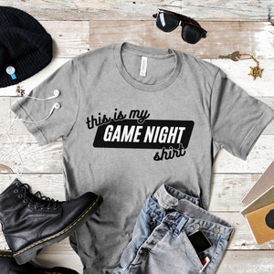 May include: Gray t-shirt with the text "This is my Game Night Shirt" printed in black.
