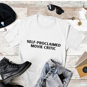May include: White t-shirt with the text "SELF-PROCLAIMED MOVIE CRITIC" printed in black.