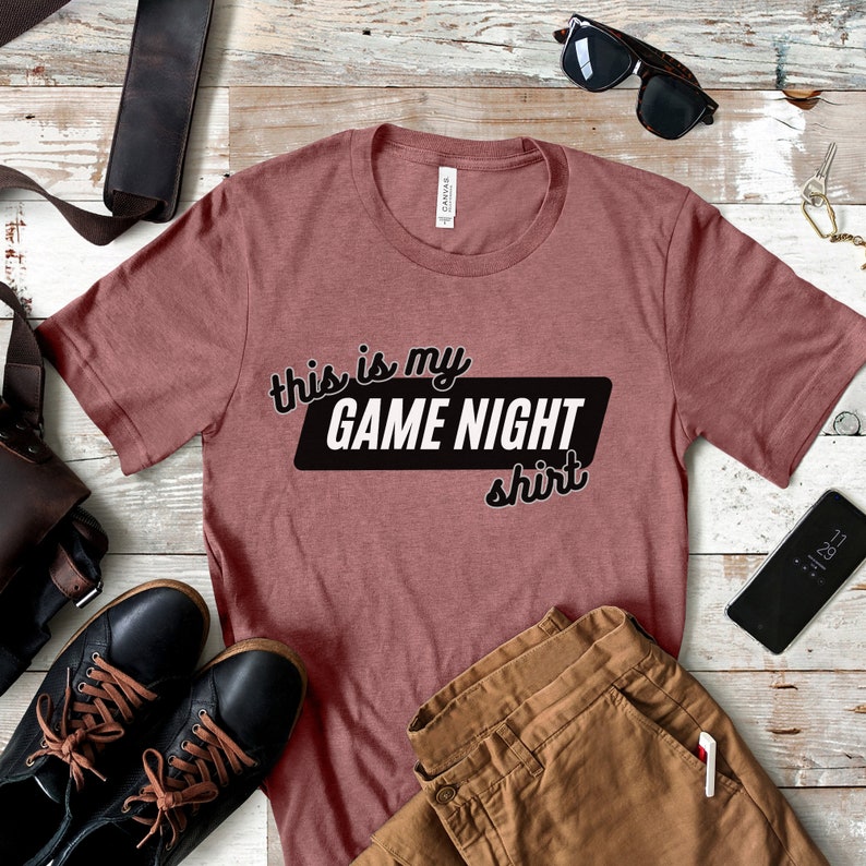 May include: A maroon t-shirt with the text "This is my GAME NIGHT shirt" in black.