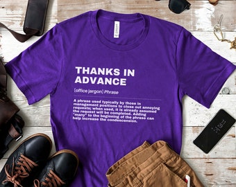 May include: Purple t-shirt with a white graphic design that defines the phrase "Thanks in Advance" as an office jargon phrase. The definition explains that the phrase is typically used by those in management positions to close out annoying requests.