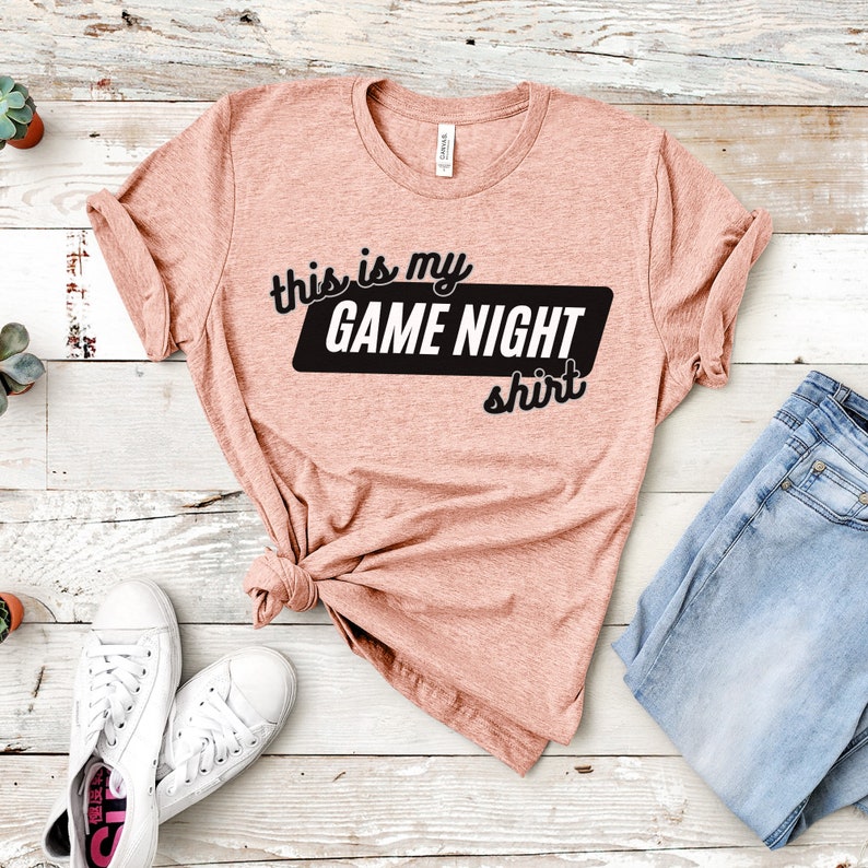 May include: A peach-colored t-shirt with the text "This is my GAME NIGHT shirt" in black lettering.