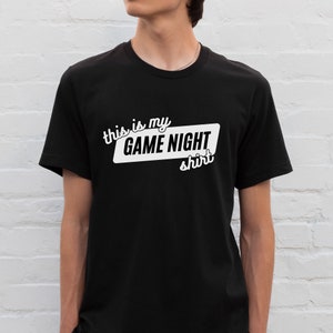 May include: A black t-shirt with white text that says "This is my GAME NIGHT shirt".