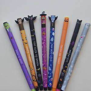 Può includere: Un set di otto penne a tema Halloween con topper a forma di personaggio e disegni stampati. Le penne riportano scritte come PEEK-A-BOO, HOO'S THERE?, TOO CUTE TO SPOOK, HOCUS POCUS, FAB-BOO LOUS, TRICK OR TREAT, MEOW-GIC e GROOWRR! con vari motivi spettrali.