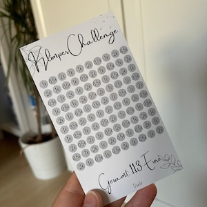 Könnte beinhalten: Eine weiße Karte mit dem Text "Klimper Challenge" in schwarzer Kursivschrift. Die Karte ist mit grauen Kreisen gefüllt, die jeweils eine Zahl oder einen Dezimalbetrag in schwarzer Schrift enthalten. Am unteren Rand der Karte steht "Gesamt: 113 Euro" in schwarzer Kursivschrift.