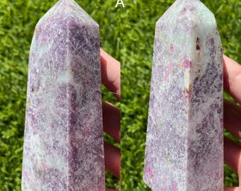 May include: A purple and white Lepidolite crystal point with a natural, raw finish. The crystal is 4.45 inches tall and weighs 262 grams. The crystal is labeled "Unicorn A".