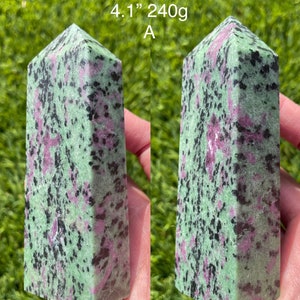 May include: A Ruby Zoisite crystal obelisk, 4.1 inches tall and weighing 240g. The stone features a mix of green, pink, and black colors. The text "Ruby Zoisite 4.1" 240g A" is visible.