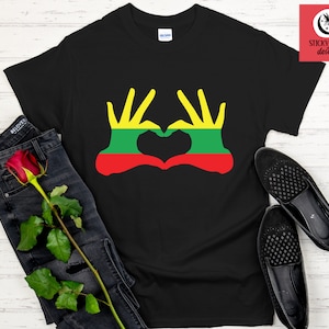 Può includere: Maglietta nera con una grafica di due mani che formano un cuore con i colori della bandiera lituana all'interno del cuore.