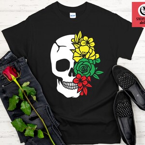Puede incluir: Camiseta negra con un diseño de calavera blanca. La cuenca del ojo de la calavera está llena de flores amarillas, verdes y rojas.