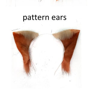 May include: A pair of orange and brown faux fur cat ears headband. The headband is white and the ears are fluffy.