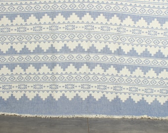 May include: A blue and white patterned throw blanket with a fringe border. The blanket has a geometric design with white diamonds and triangles on a blue background.