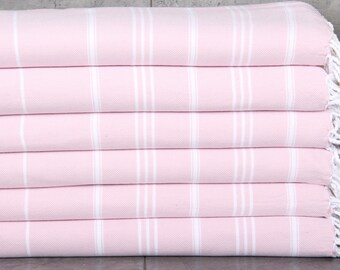Può includere: Una pila di sei asciugamani a righe rosa e bianche. Gli asciugamani sono piegati ordinatamente, con frange bianche visibili sull'asciugamano superiore. Gli asciugamani hanno un aspetto morbido e strutturato, e le righe sono verticali.