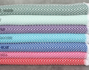 May include: A stack of seven towels in various colors, including dark green, mint, purple, turquoise, sax blue, fuchsia, and red. Each towel has a white chevron pattern.